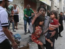 A Palestinian girl holds two children as she stands on a street in Gaza City. Photograph: Bashar Taleb/AFP/Getty Images. Image by The Guardian