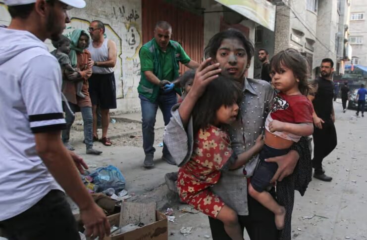 A Palestinian girl holds two children as she stands on a street in Gaza City. Photograph: Bashar Taleb/AFP/Getty Images. Image by The Guardian